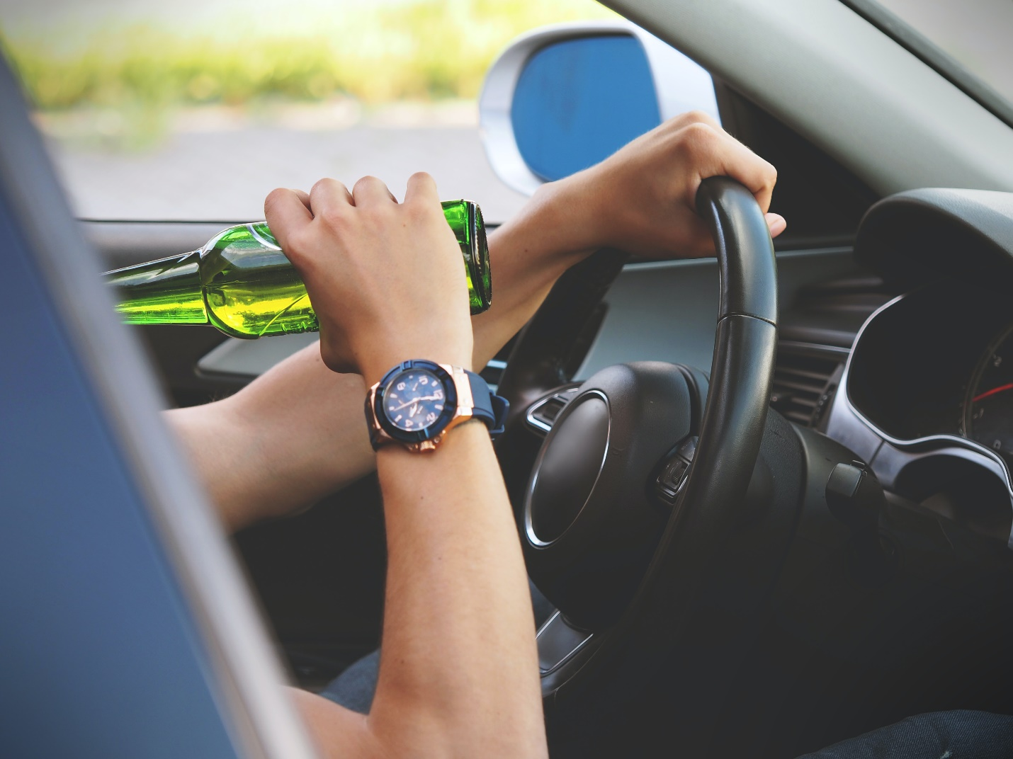 A person drinking alcohol while driving.